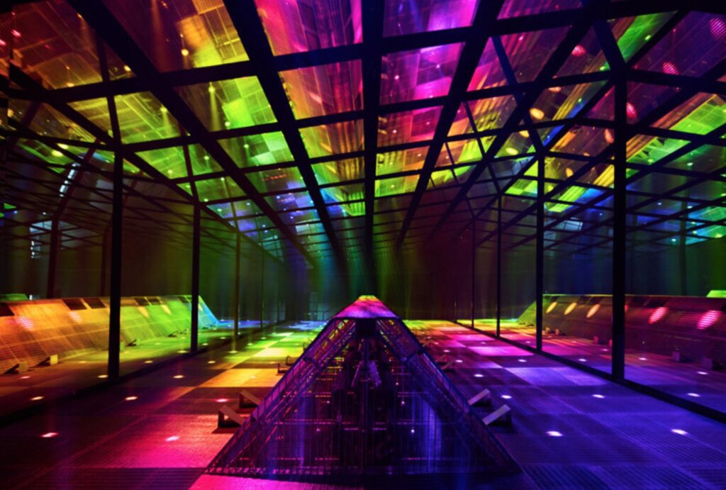 Pulled-back view of the space with overhead cage and central viewing rainbowcolors